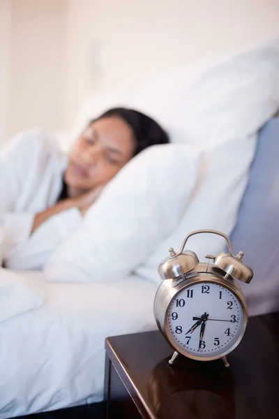 Reloj despertador junto a la cama en el que la mujer está durmiendo —  Fotos de Stock