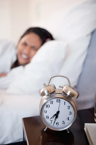 ベッドの中で女性の横に鳴っているアラーム時計 — ストック写真