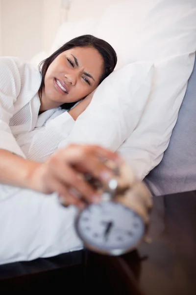 Woman getting pain in the ears by alarm clock — Stock Photo, Image