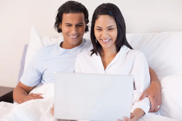 Couple assis sur le lit avec leur ordinateur portable — Photo