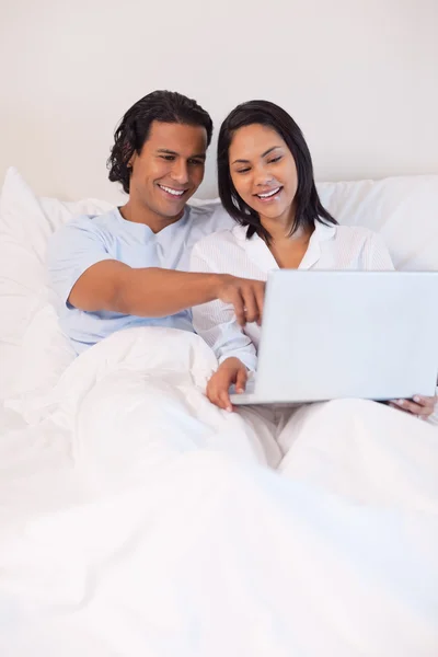 Paret sitter på sängen med sin bärbara dator — Stockfoto