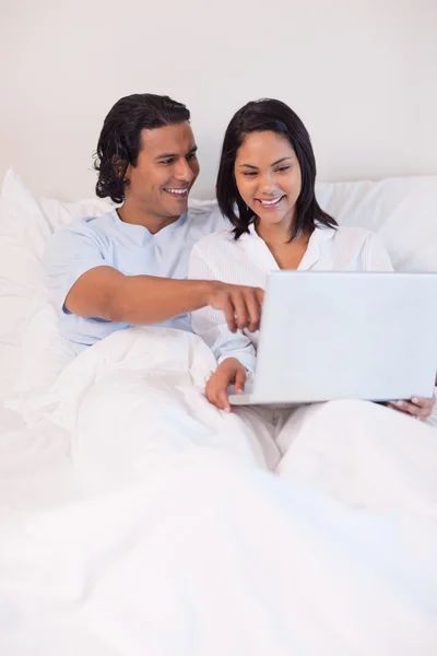 Paar zittend op het bed surfen op het web — Stockfoto