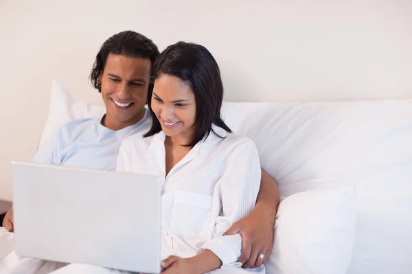 Paret sitter på sängen med hjälp av internet — Stockfoto