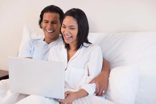 Couple using their laptop while sitting on the bed — Stok fotoğraf