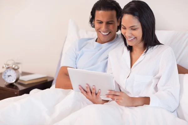 Pár sedí na posteli, pomocí počítače tablet pc — Stock fotografie