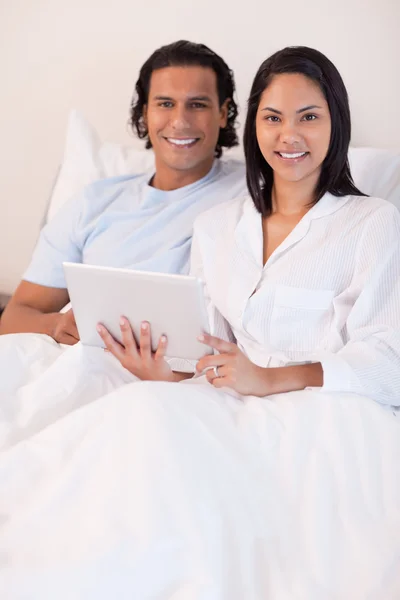 Casal usando tablet pc em sua cama — Fotografia de Stock