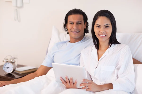 Paar sitzt mit Tablet-PC auf dem Bett — Stockfoto