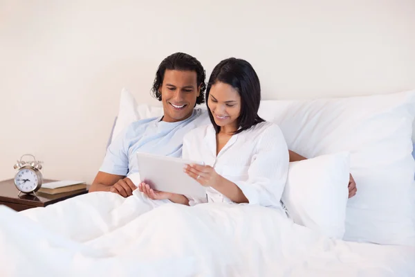 Paar surft auf dem Bett im Internet — Stockfoto