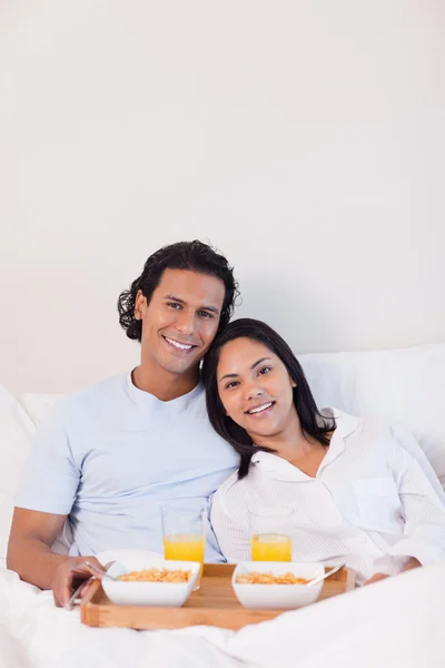 Lyckliga paret med frukost i sängen — Stockfoto