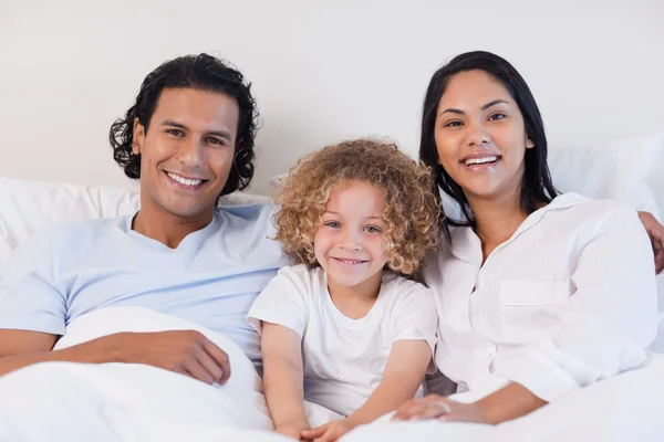 Happy family sitting on the bed together — Stock Photo, Image