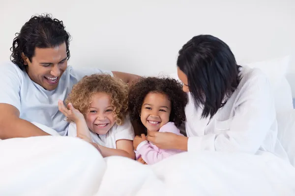 Усміхнена сім'я сидить на ліжку — стокове фото