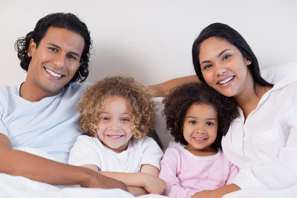 Smiling family sitting on the bed together — Stock Photo, Image