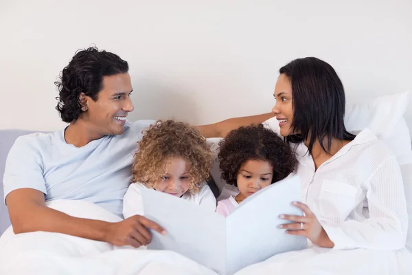 Famiglia che legge una storia in camera da letto — Foto Stock