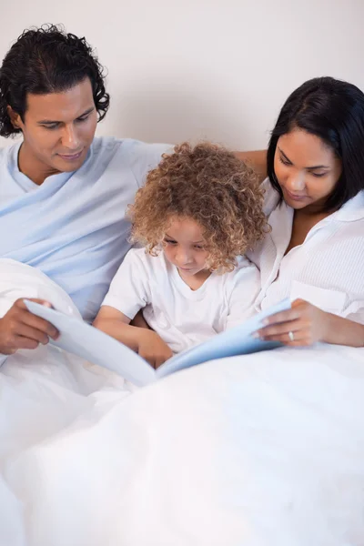 Οικογένεια κάθεται στο κρεβάτι ανάγνωση μια ιστορία — Φωτογραφία Αρχείου