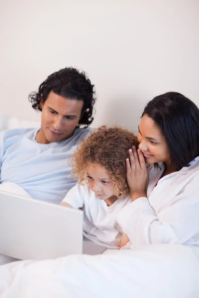 Família sentada na cama com laptop — Fotografia de Stock