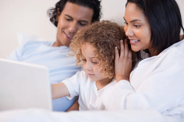 Família sentada na cama com laptop juntos — Fotografia de Stock