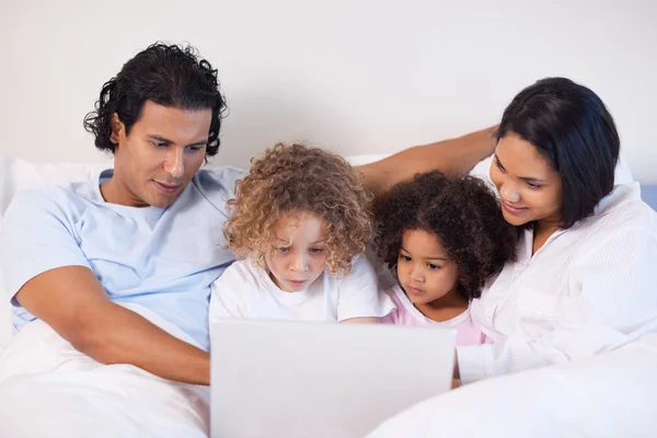 Internet'te sörf yatağın üzerine oturan aile — Stok fotoğraf