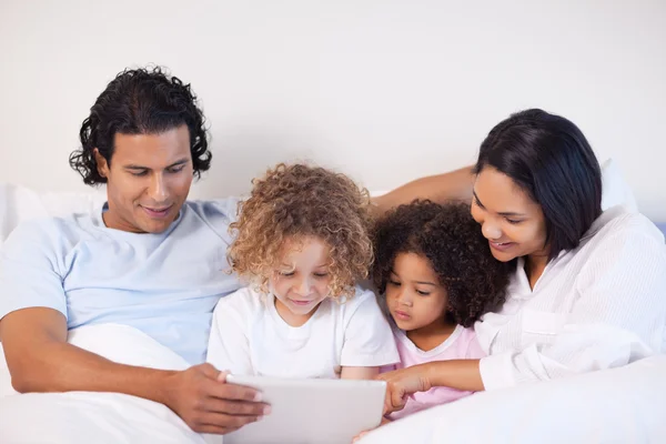 Family sitting on the bed surfing the web — Stock Photo, Image