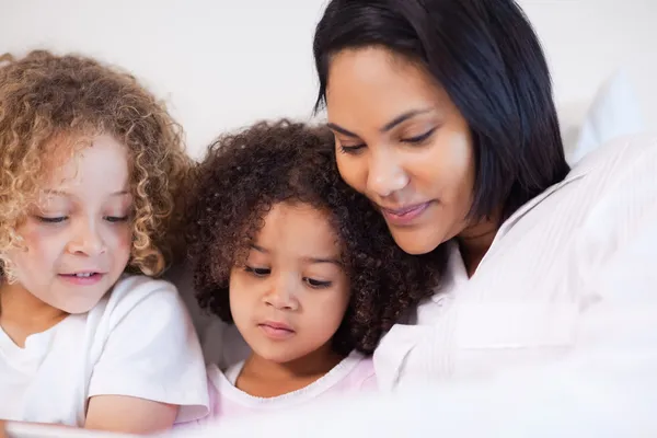 Woman sitting on the bed with her daughters — Stock Photo, Image