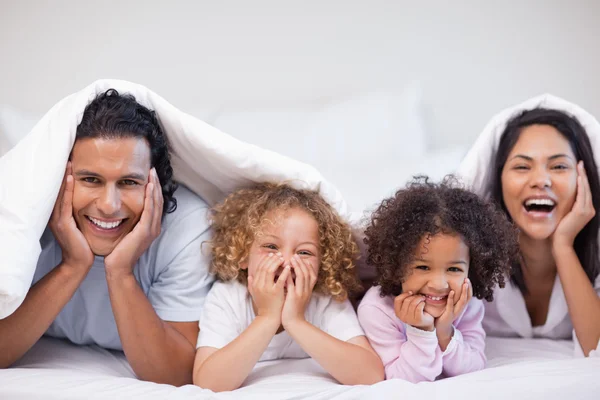 Família alegre escondida sob o cobertor — Fotografia de Stock