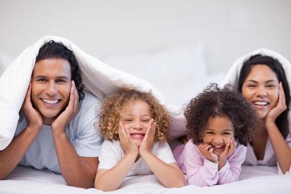 Счастливая семья прячется под одеялом — стоковое фото