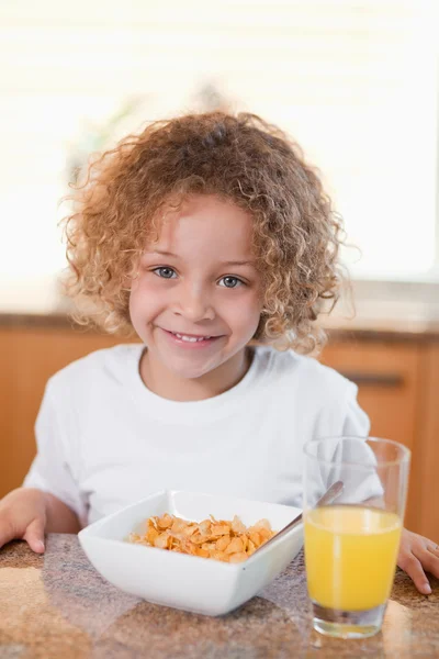 Šťastná dívka s obilovinami a pomerančový džus k snídani — Stock fotografie