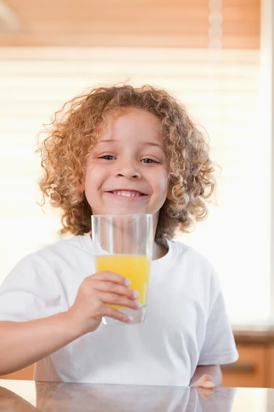 Sonriente chica teniendo jugo de naranja en la cocina — Foto de Stock