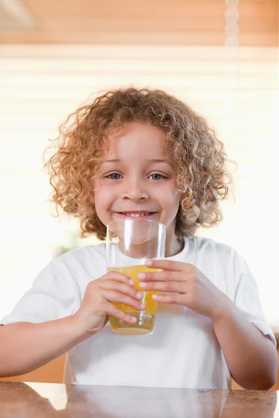 Happy girl drinking orange juice in the kitchen — Stock Photo, Image