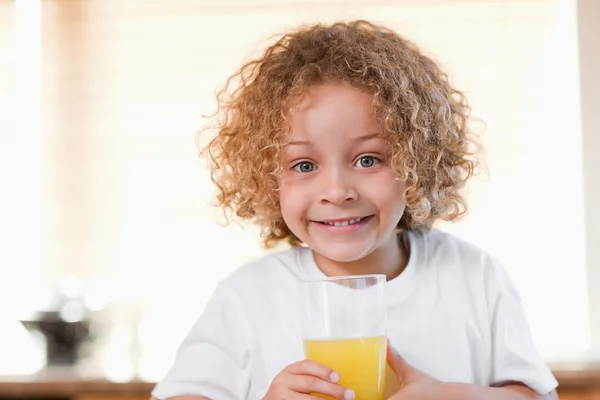 Chica con un vaso de jugo de naranja en la cocina — Foto de Stock