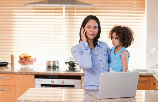 Anne ve kızı ile cep telefonu ve laptop içinde mutfak TOG yardımı — Stok fotoğraf