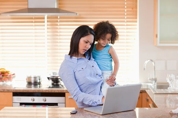 Madre e hija usando el portátil en la cocina juntas —  Fotos de Stock