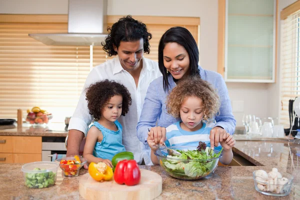 Семья готовит салат вместе на кухне — стоковое фото