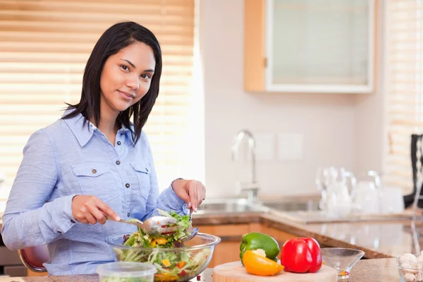 Woman stirring her salad in the kitchen — Stock Photo, Image