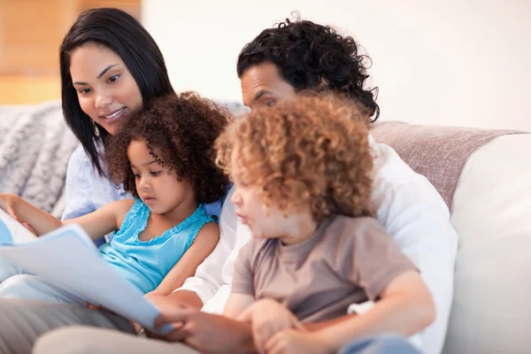 Happy family on the sofa looking at photo album together — Stock Photo, Image