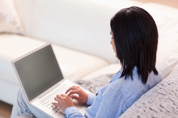 Vrouw die werkt op haar laptop in de woonkamer — Stockfoto