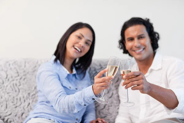 Пара празднующих с игристым вином на диване — стоковое фото