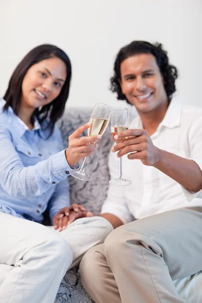 Oturma odasında köpüklü şarap ile kutlayan çift — Stok fotoğraf