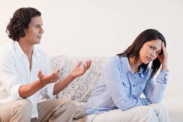 Мужчина на диване пытается извиниться перед своей девушкой — стоковое фото