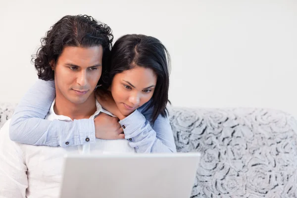 Vrouw haar vriendje dat op zijn laptop werkt knuffelen — Stockfoto