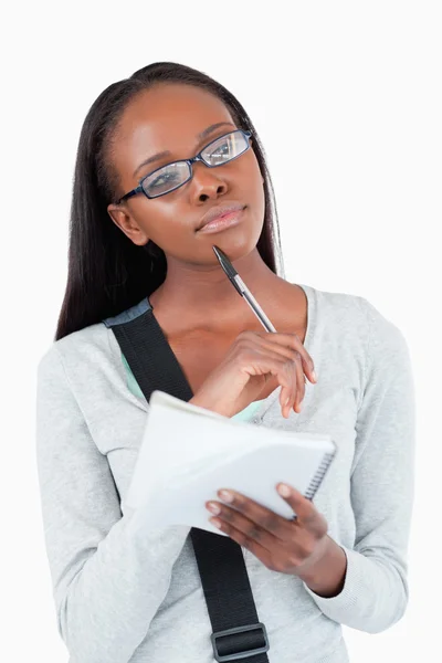 Young woman with notepad and glasses in thoughts Stock Photo