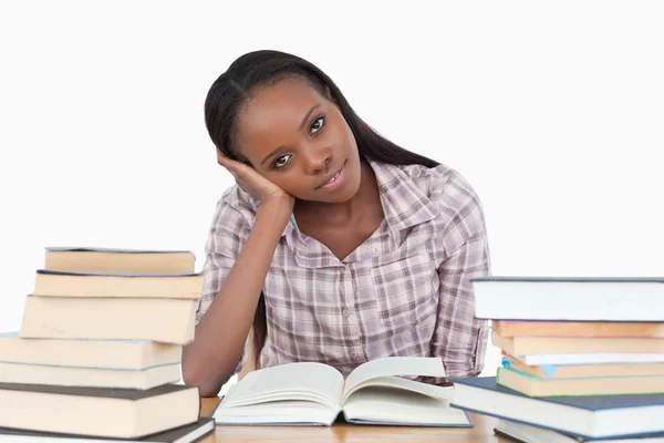 Young woman sitting on her desk with piles of books — Stock Image Young woman sitting on her desk with piles of books Stock Photo
