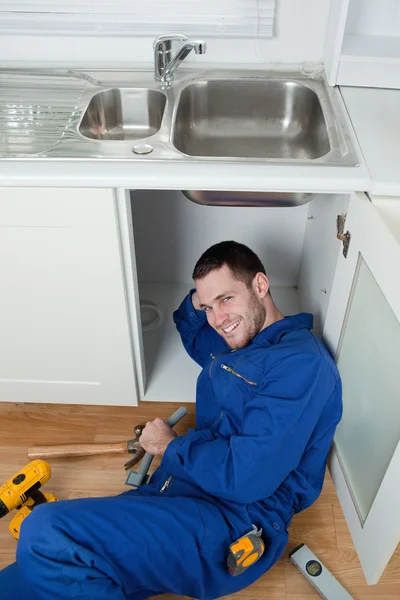 Portrait of a smiling repairman fixing a sink Stock Image