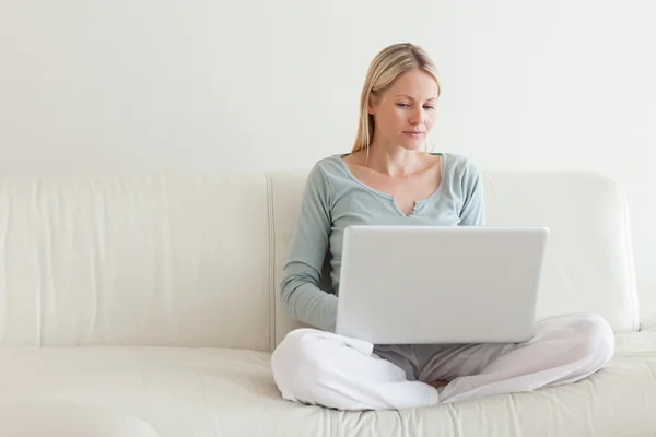 Woman sitting cross legged on the couch with her notebook — Stock Photo, Image