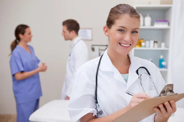 Smiling doctor writing on clipboard Stock Photo