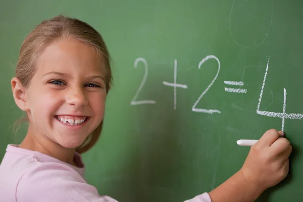 Happy schoolgirl writing a number Stock Image