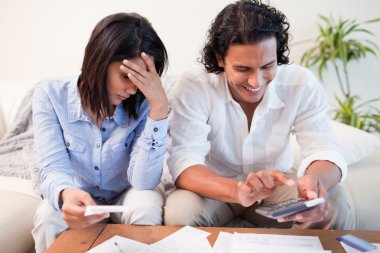 Couple checking their bills in the living room clipart