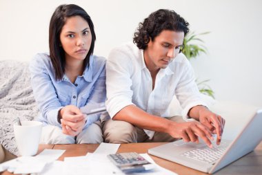 Couple checking their bank accounts online in the living room clipart