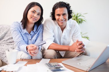 Couple doing online banking in the living room clipart