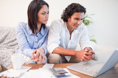 Couple sitting in the living room doing online banking clipart