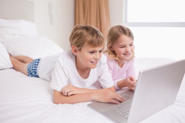 Smiling children using a notebook clipart